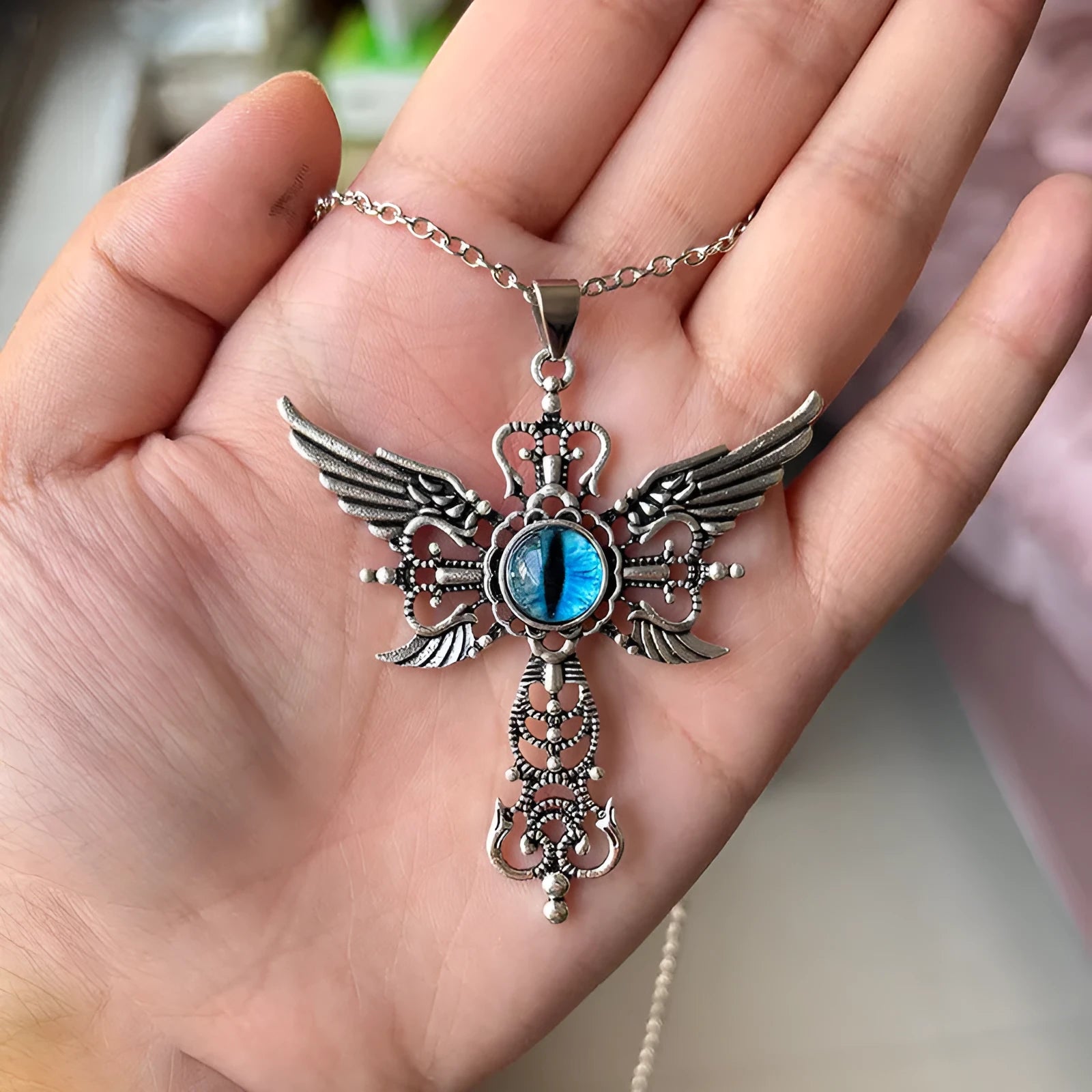 Geometric devil wings and cross alloy pendant necklace on a chain in blue colour.
