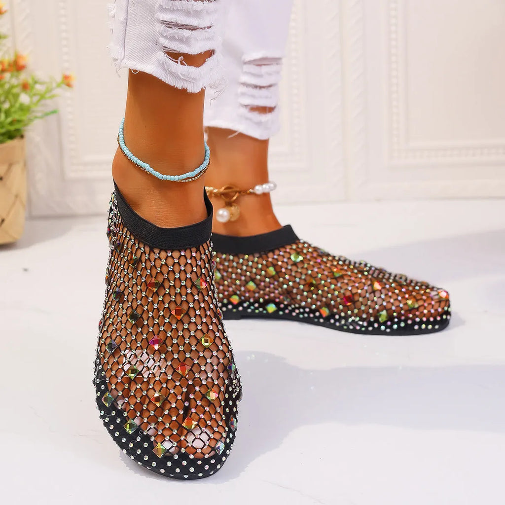 Women's flat sandals with colourful rhinestones on a mesh upper and rubber sole.