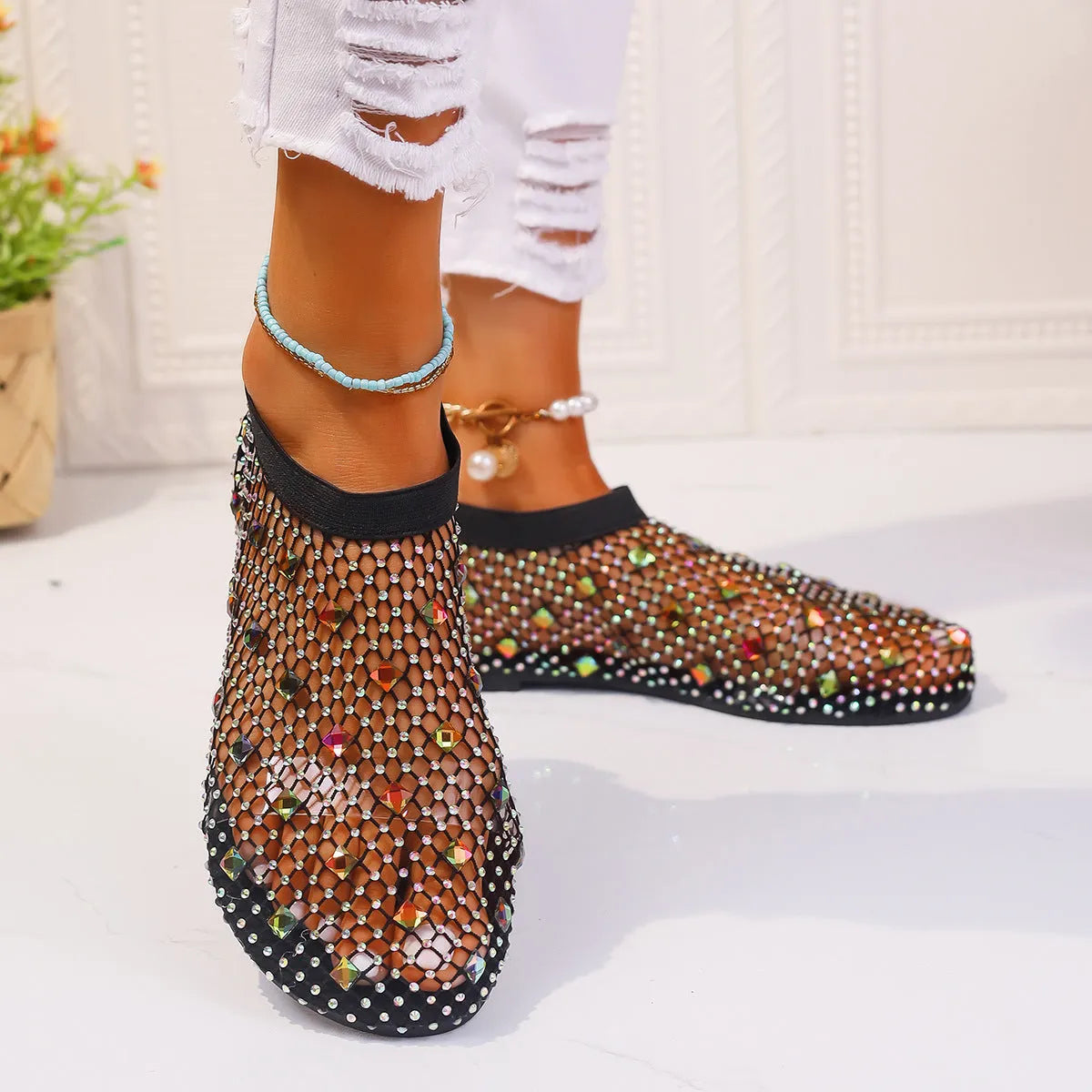 Women's flat sandals with colourful rhinestones on a mesh upper and rubber sole.