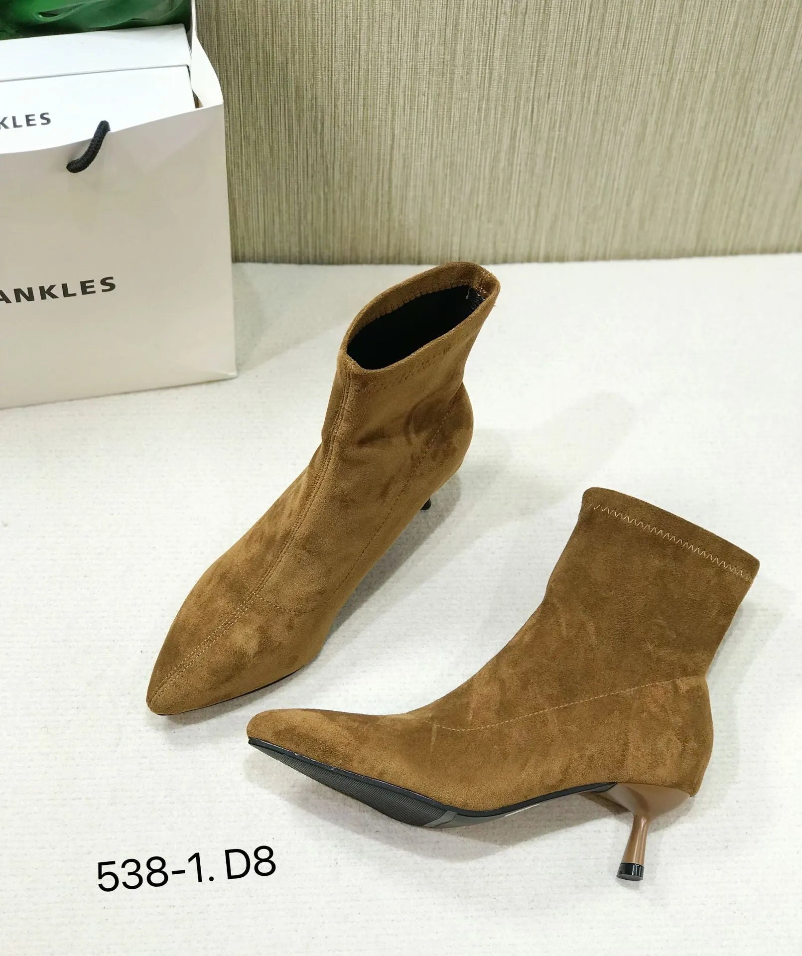 Black pointed toe women's ankle boots with stiletto heel on a plain background