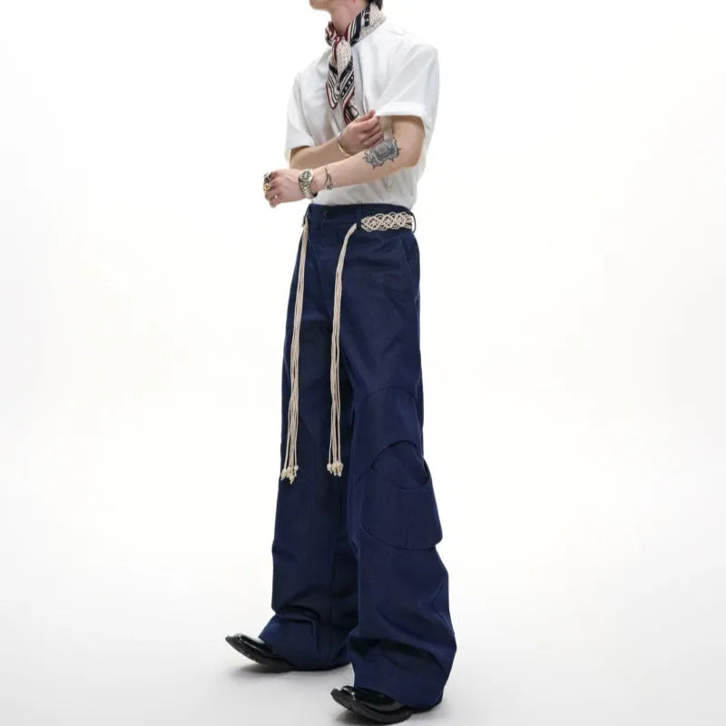 Man wearing dark grey straight-leg cotton trousers with a tassel detail and loose fit.