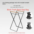 Black foldable outdoor iron trash rack with wooden handle holding a white bin bag.