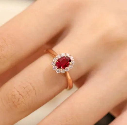 Women's silver ring with gold pigeon design and large red gemstone inlay on a floral pattern band.