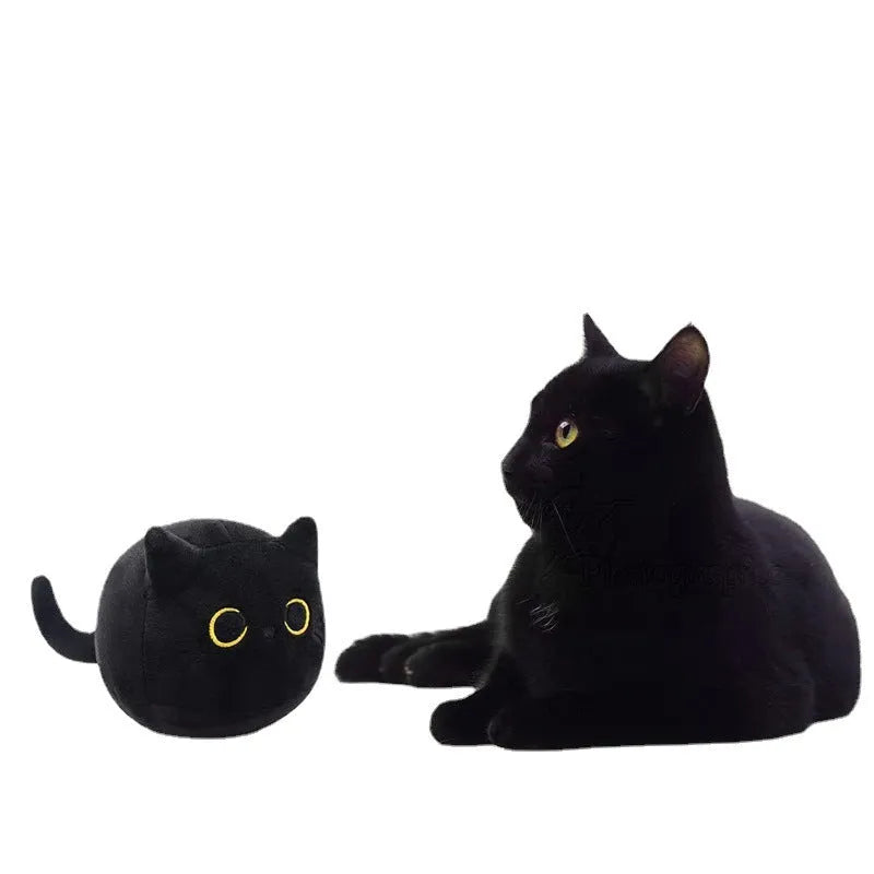 Black fluffy cat plush toy stuffed animal on a sofa, used as a soft cushion.