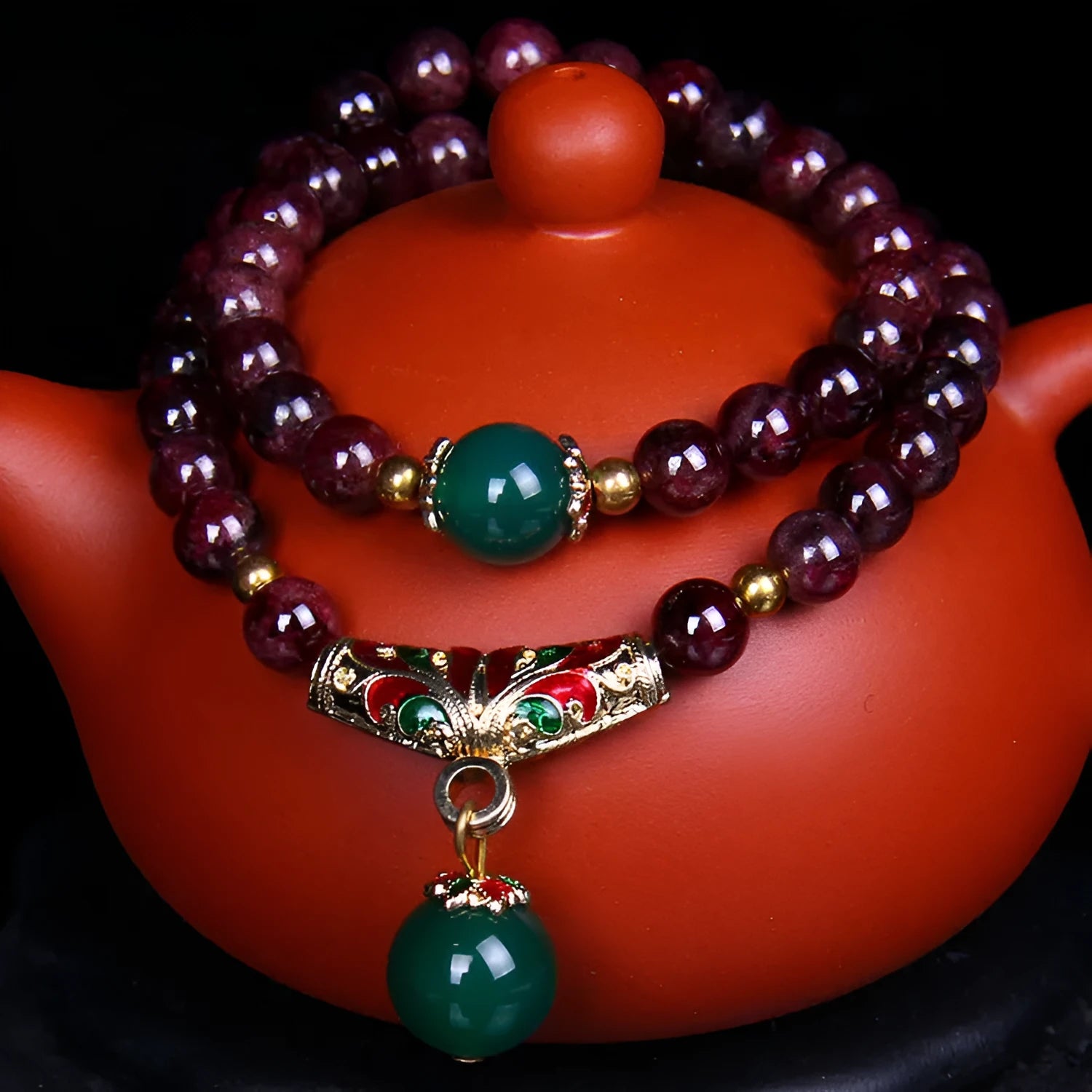 Red garnet bracelet with 7mm beads and a golden toad charm on wrist.