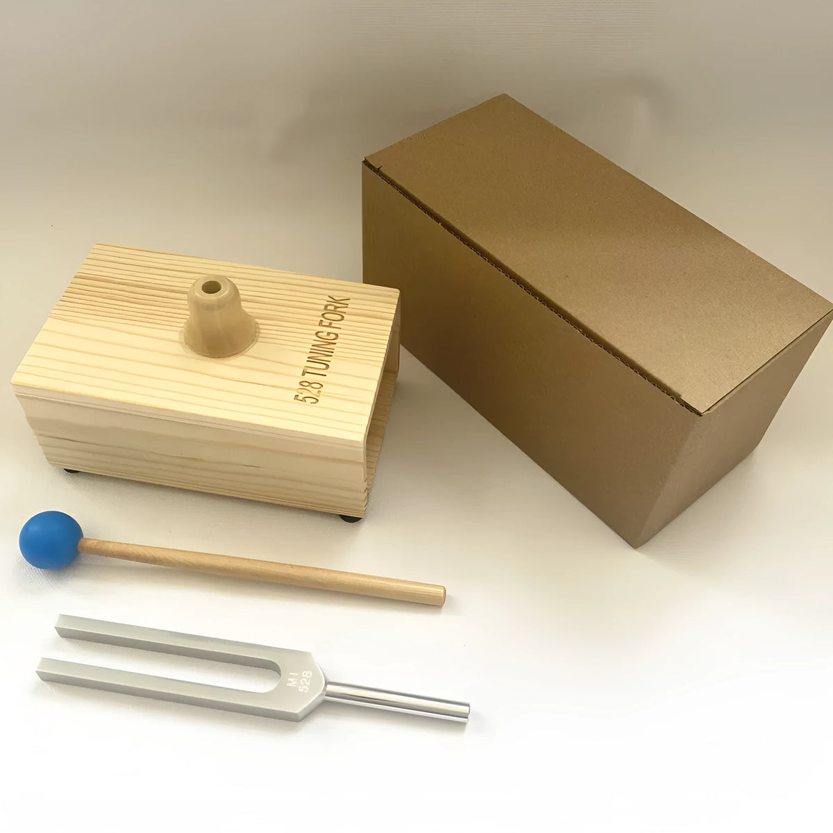 Aluminium alloy 432 Hz tuning fork with a matching speaker unit on a kraft paper box.