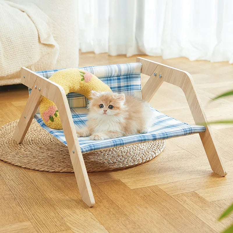 Green wooden elevated cat hammock bed with cloth sling on a light floor.