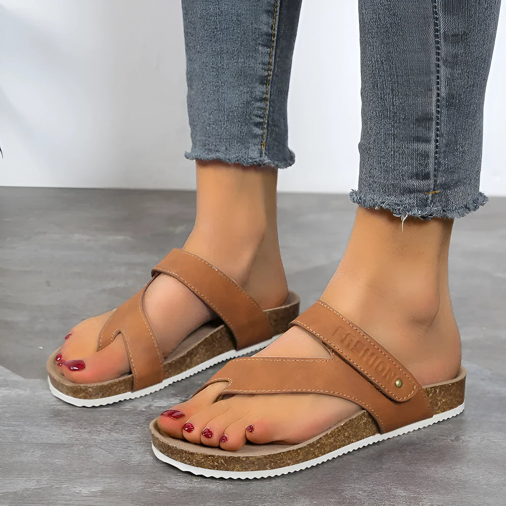 Flat toe ring flip-flops in blue with a thick foam sole on a wooden floor.