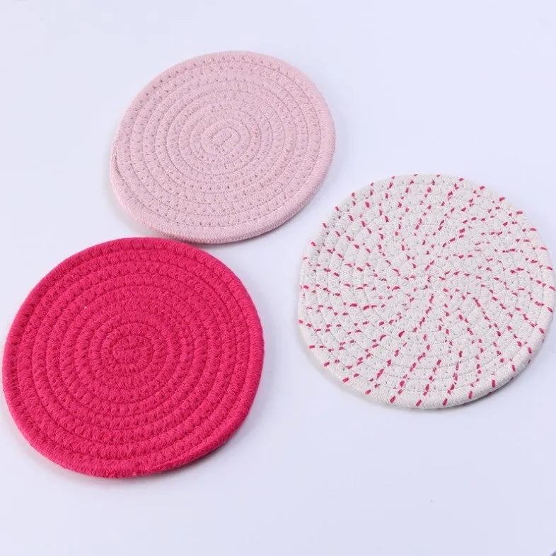 Set of three round cotton cord coasters in blue colour, 18cm diameter, on a table.