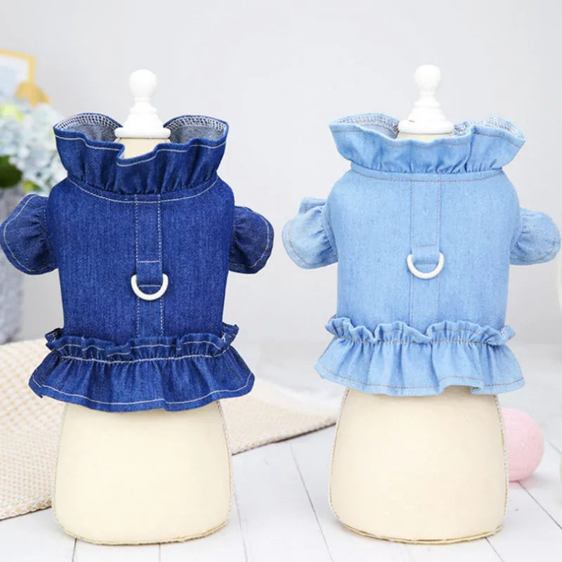 Blue denim vest dress for dog with ruffle trim and metal leash hook on chest.