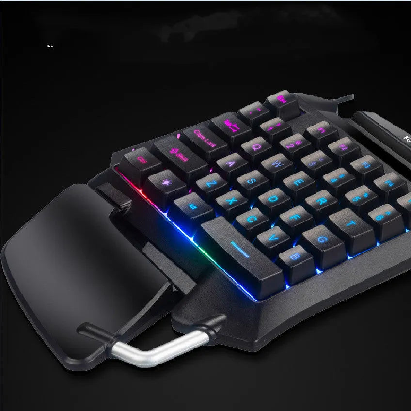 Black left-handed one-handed gaming keyboard with palm rest and shortcut keys on a desktop.