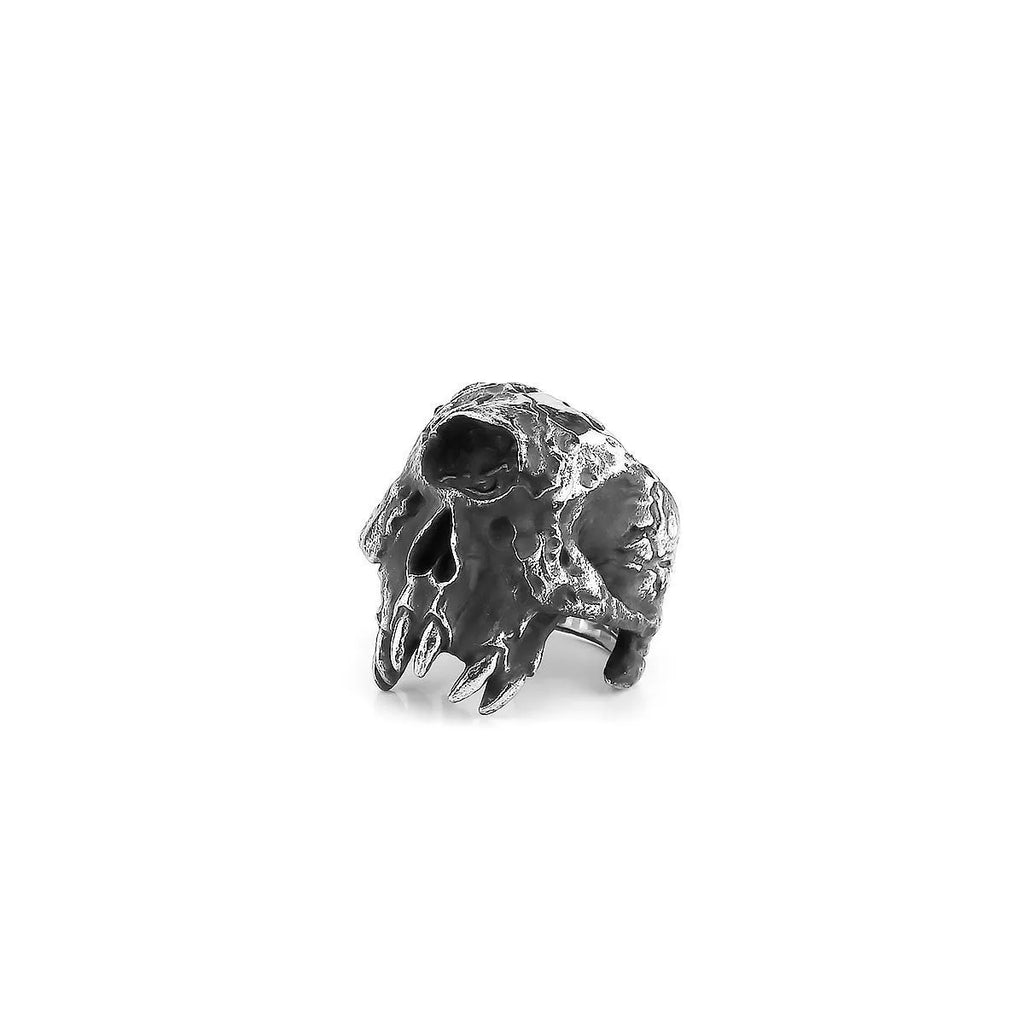 Close-up of a silver-toned alloy ring featuring a detailed one-eyed skull design on a black background.