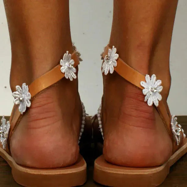 Brown women's Roman sandals with flat rubber soles, floral decoration, and herringbone toe shaping