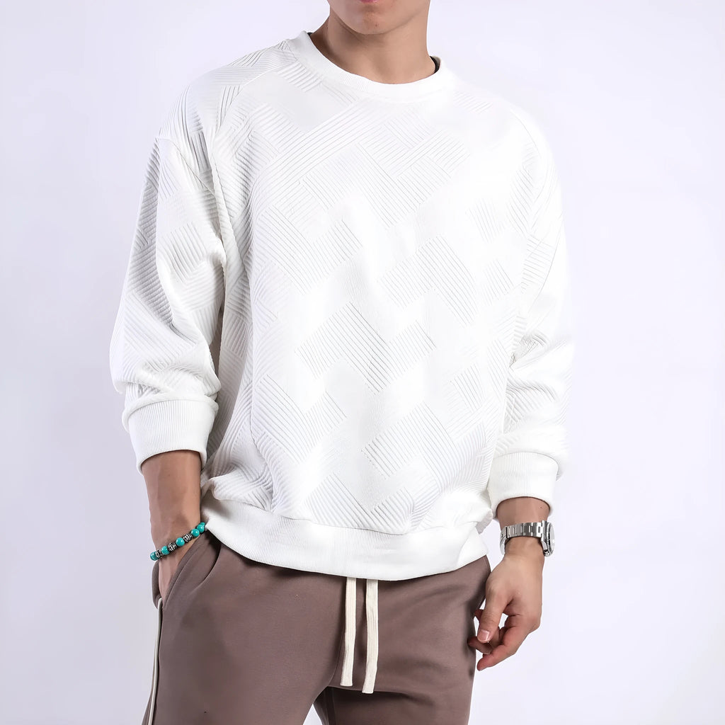 Man wearing a loose-fitting, long-sleeved army green pullover sweater with a textured twill jacquard pattern.