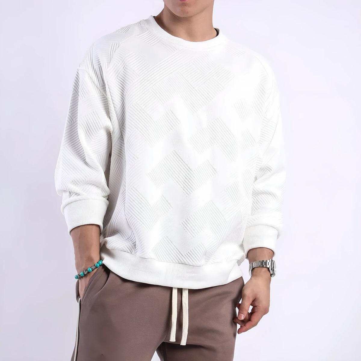 Man wearing a loose-fitting, long-sleeved army green pullover sweater with a textured twill jacquard pattern.