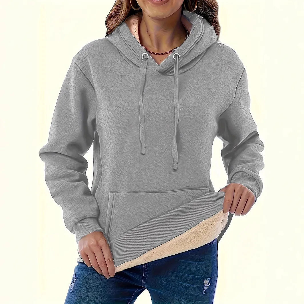 Woman wearing a loose black hooded sweater with a raised 3D pattern on the fabric.