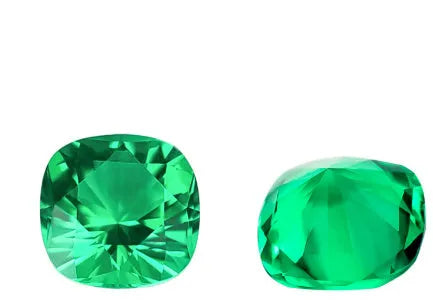 Cultivated emerald loose gemstones in round and fancy cut shapes on a dark background.