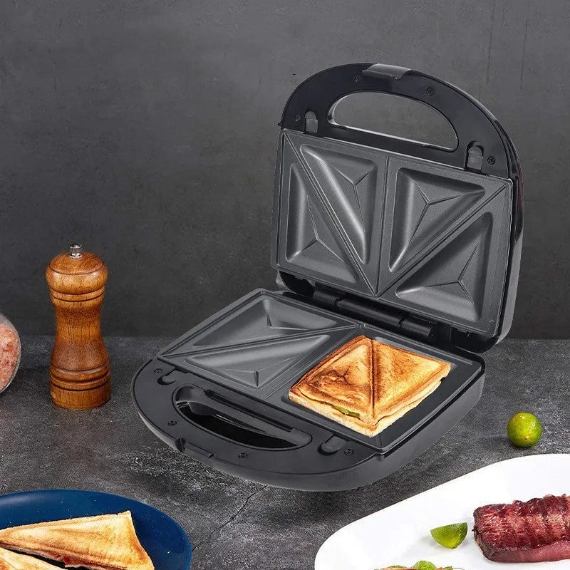Black electric sandwich pan with stainless steel lid on a kitchen countertop.