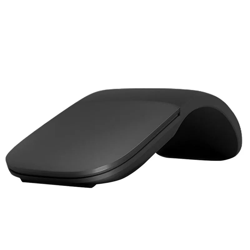 A closed black folding Bluetooth wireless mouse showing its compact size next to a laptop.