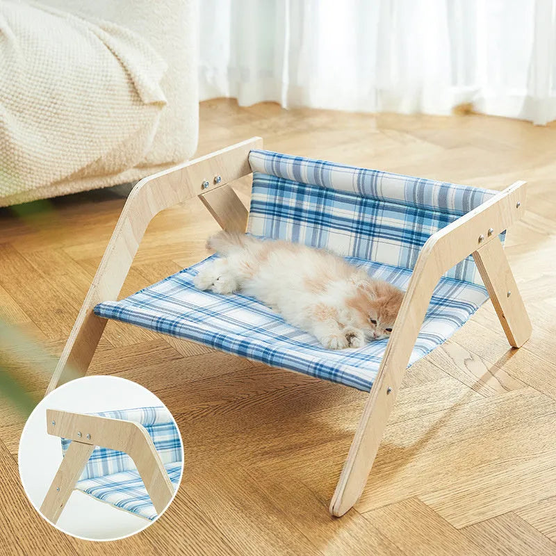 Green wooden elevated cat hammock bed with cloth sling on a light floor.
