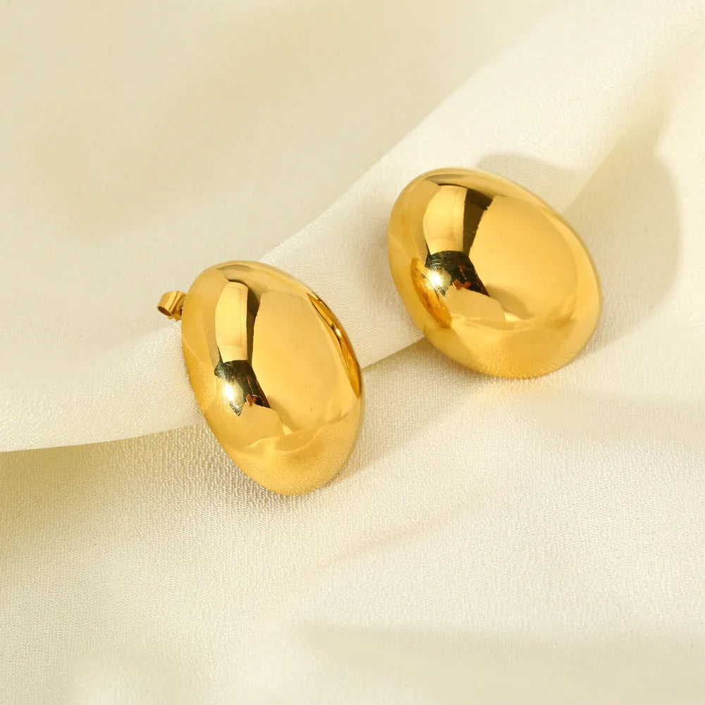 A pair of geometric gold-coloured ear studs with a glazed finish and exaggerated line details on a white background.