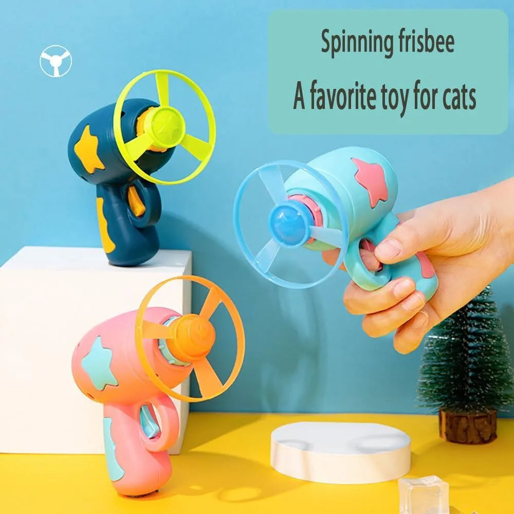 Blue interactive cat toy gun launcher with a mounted pink plastic frisbee, shown with a second frisbee disc.