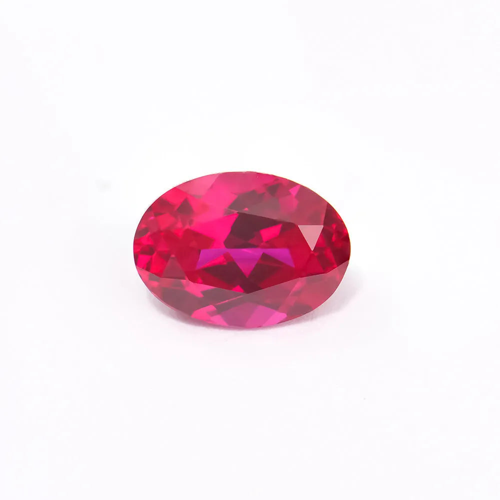 Cultivated pigeon blood red ruby gemstone showing its colour and faceted cut on a plain background.