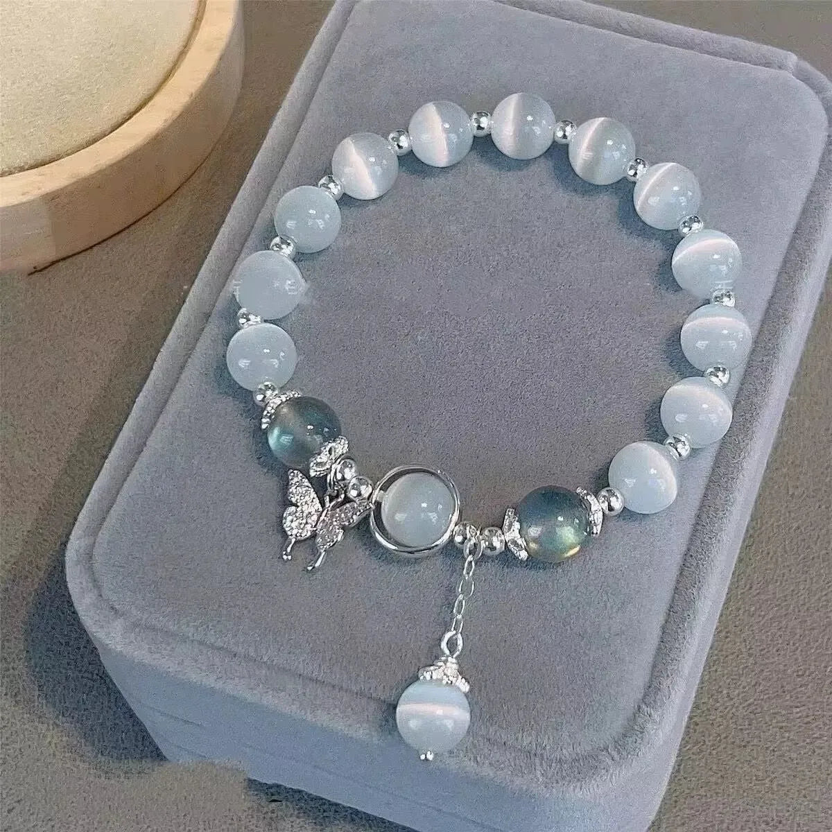 Women's handcrafted glass bead bracelet with butterfly design elements and grey colour tones