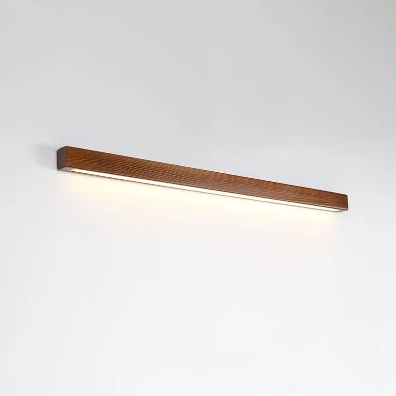 Modern walnut-colour wood log strip wall lamp with integrated LED lighting mounted on a wall.