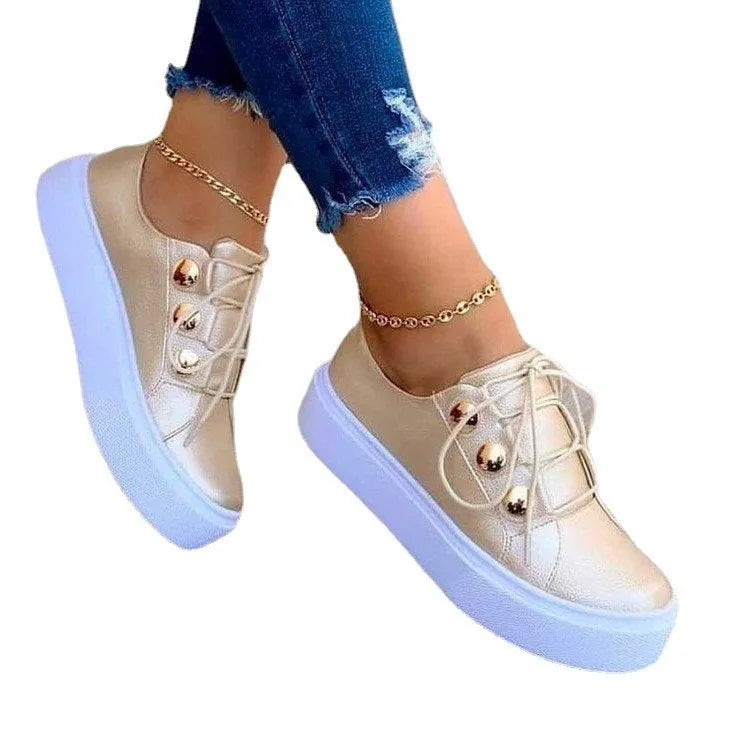 Women's white lace-up flat sneakers with silver rivet details on the round toe.