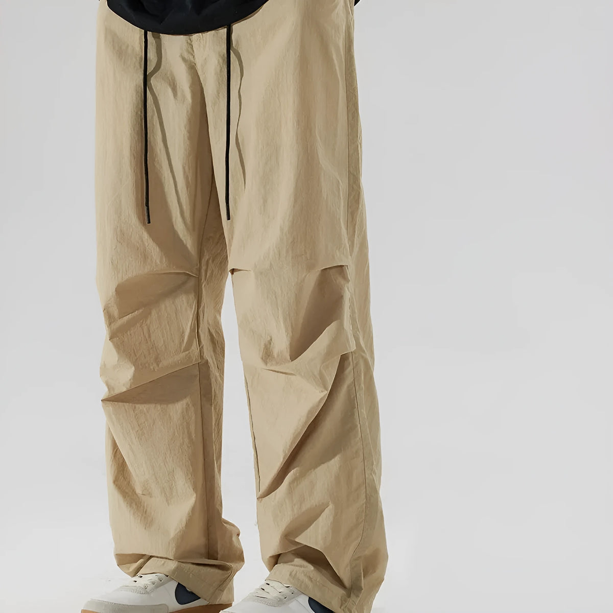 Man wearing loose straight-leg casual trousers in thin ice silk nylon fabric, shown in khaki colour.