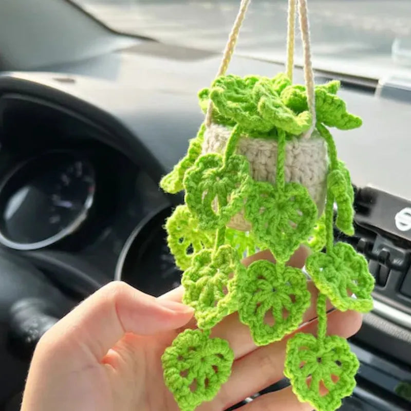 Green and white knitted wool car plant decoration basket with white hanging cord.