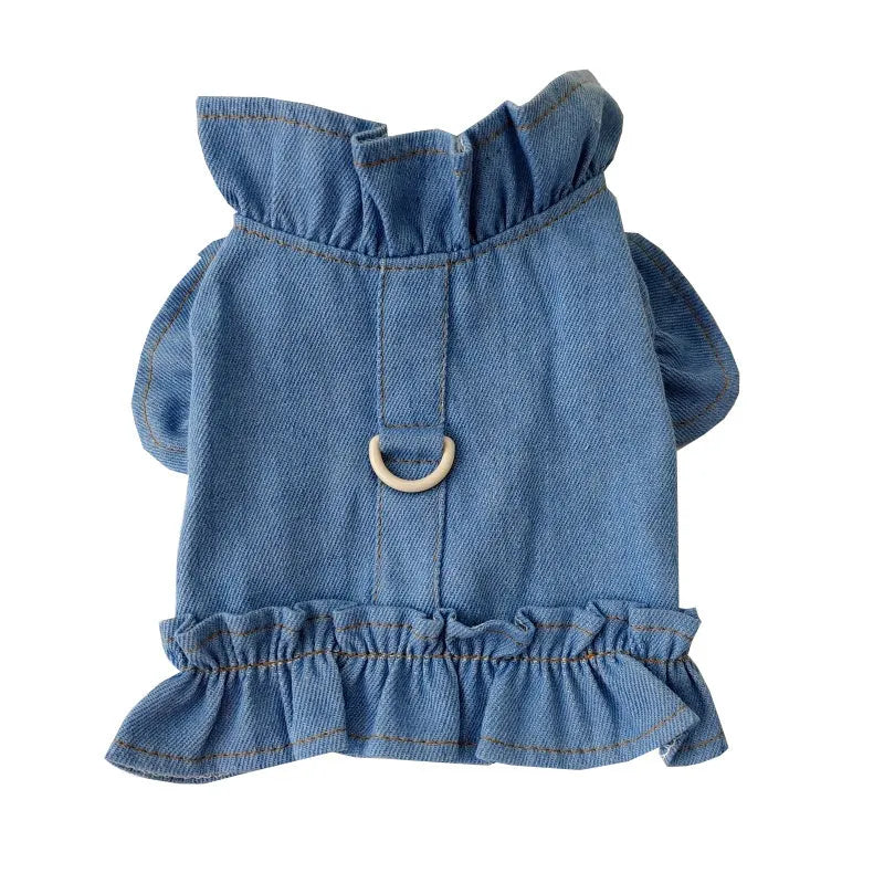 Blue denim vest dress for dog with ruffle trim and metal leash hook on chest.