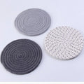 Set of three round cotton cord coasters in blue colour, 18cm diameter, on a table.