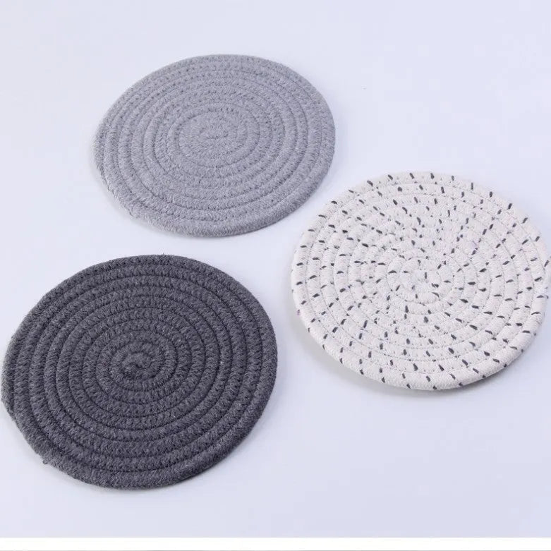 Set of three round cotton cord coasters in blue colour, 18cm diameter, on a table.