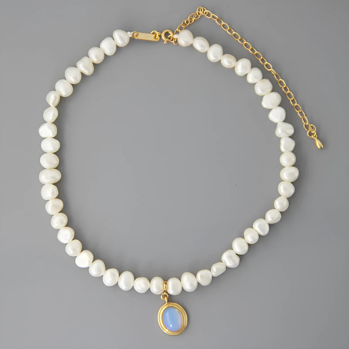 Geometric sterling silver necklace with irregular pearl pendant on a silver chain.