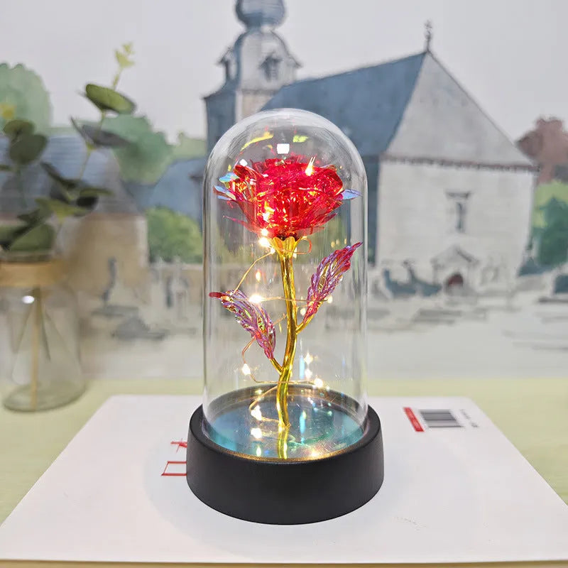 Small glass night lamp with plastic flowers on a black base.