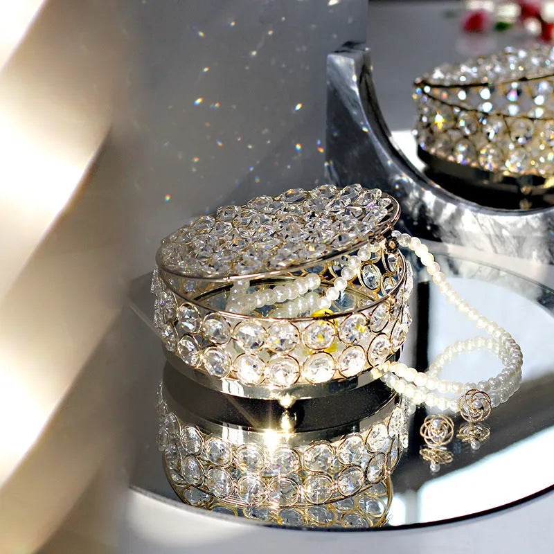 Transparent crystal glass jewelry box with a French gold metal frame on a table.