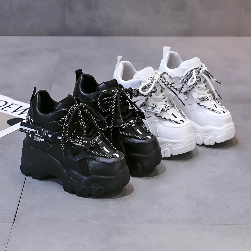 Women's white low-top platform trainers with mesh panels and a black cross-strap over the vamp.