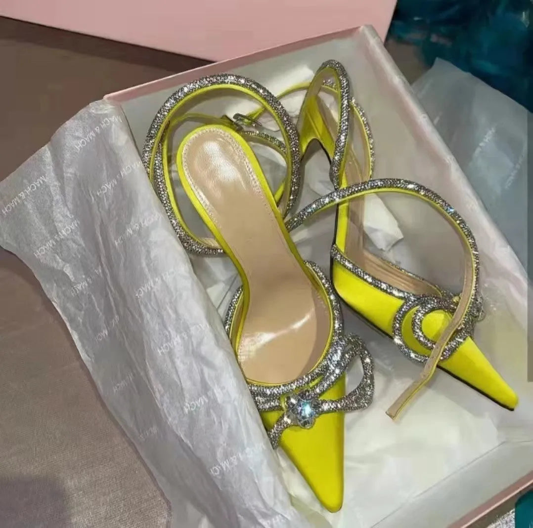 Women's black stiletto heel sandals with a silk back bandage and pointed toe, showing buckle fastening.