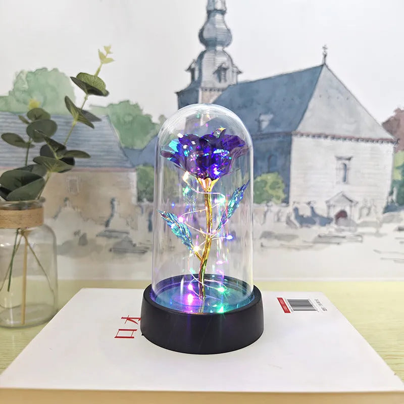 Small glass night lamp with plastic flowers on a black base.