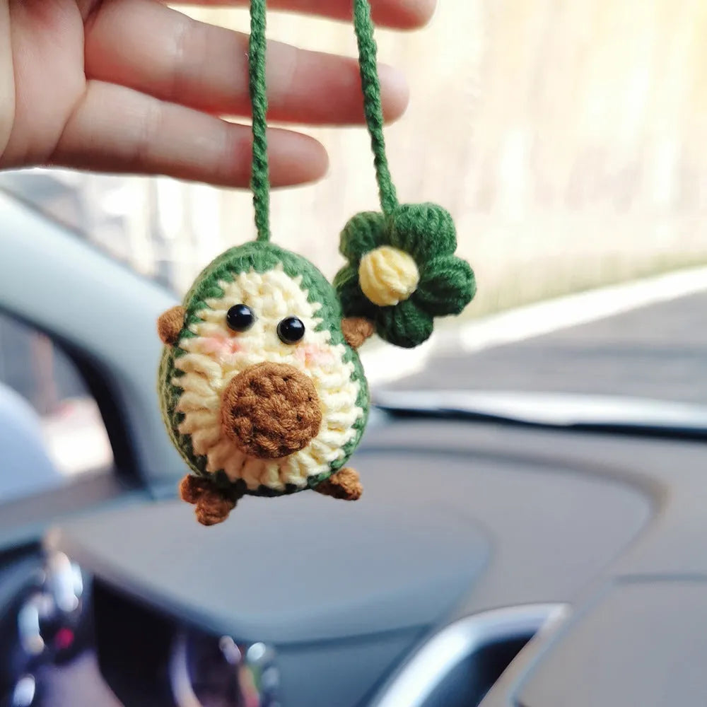 Handmade crocheted avocado with rainbow flower car pendant in wool yarn.
