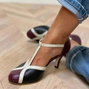 Women's blue and pink round toe stiletto high heel pump with button fastening.