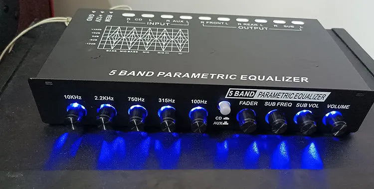 Black car audio EQ tuning amplifier with control knobs for subwoofer and seven-band equaliser.