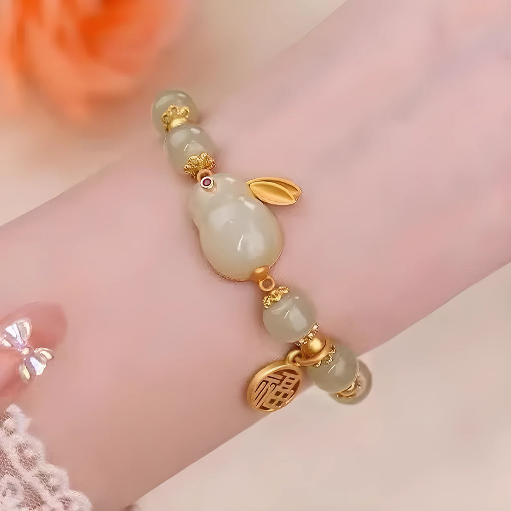 Women's black bracelet with a green jade hare charm, fu character symbol and lily motif design.