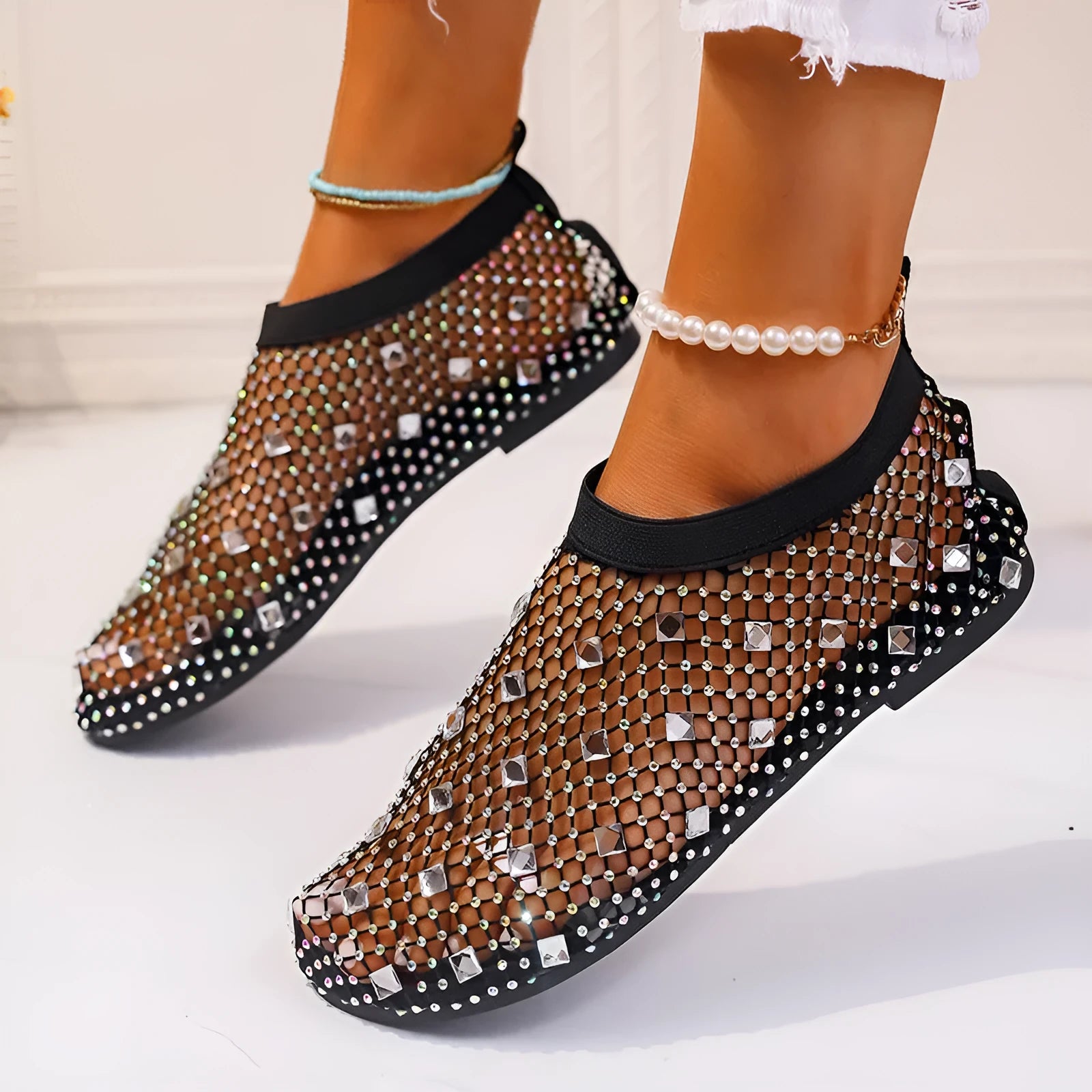 Women's flat sandals with colourful rhinestones on a mesh upper and rubber sole.