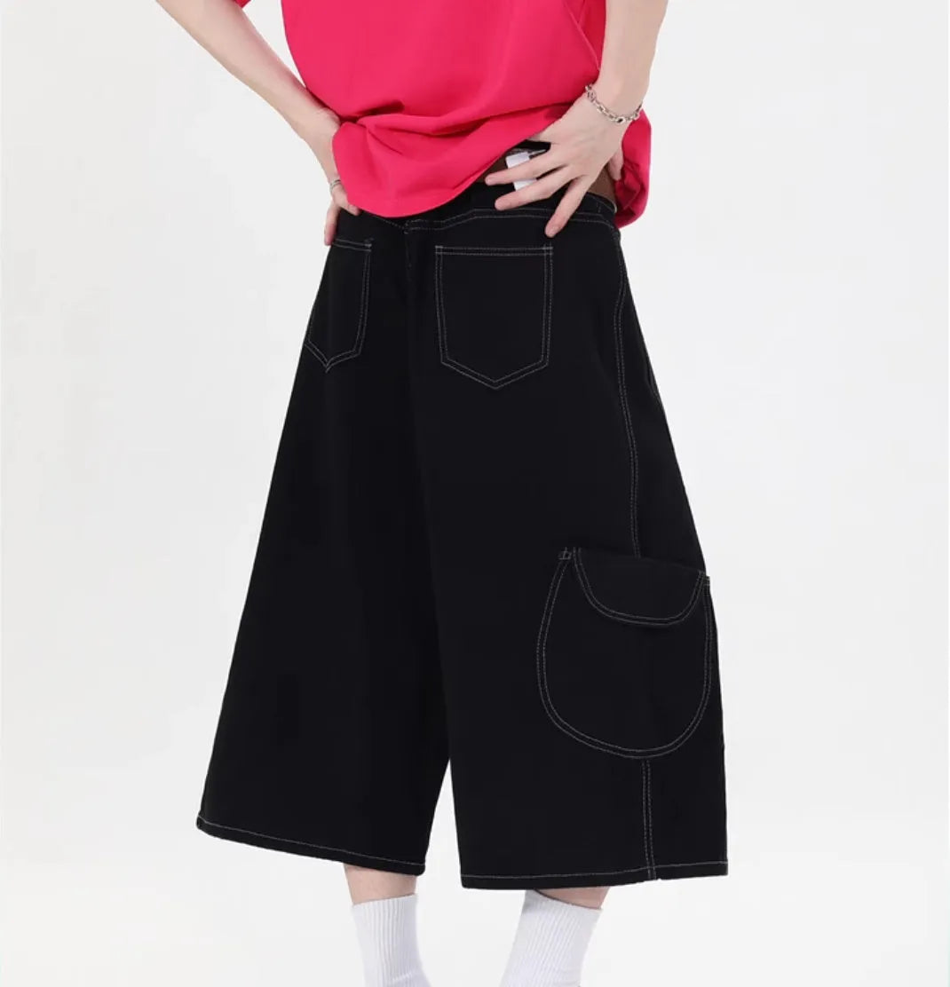 Red denim retro workwear shorts with multiple pockets and a wide-leg cropped fit on a model.