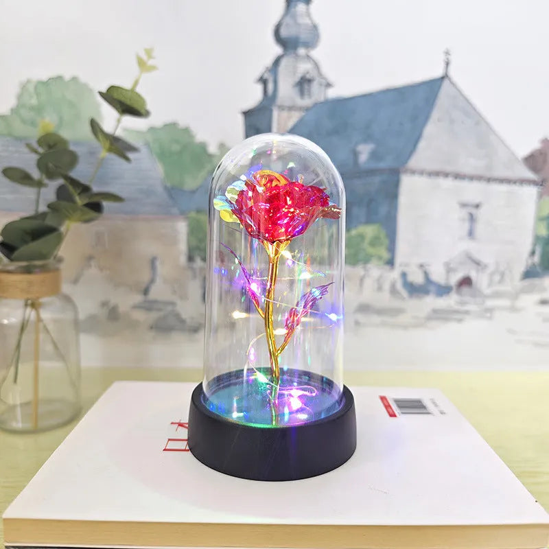 Small glass night lamp with plastic flowers on a black base.