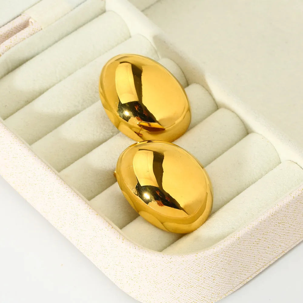 A pair of geometric gold-coloured ear studs with a glazed finish and exaggerated line details on a white background.