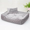 Polka dot printed cloth dog bed with matching embroidery pillow in grey, shown in a room setting.